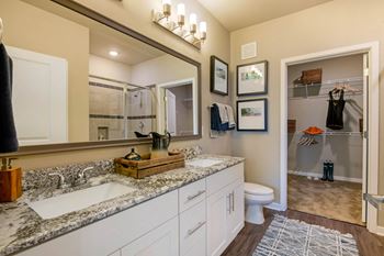 A bathroom with a marble countertop and a large mirror above it at JTB Apartments, Jacksonville, FL