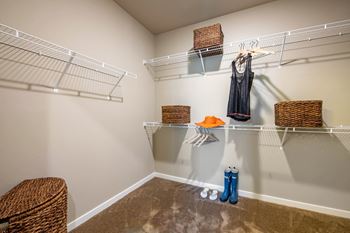 A room with a carpeted floor and a wall-mounted shelf with baskets and a hanging garment at JTB Apartments, Jacksonville, 32256