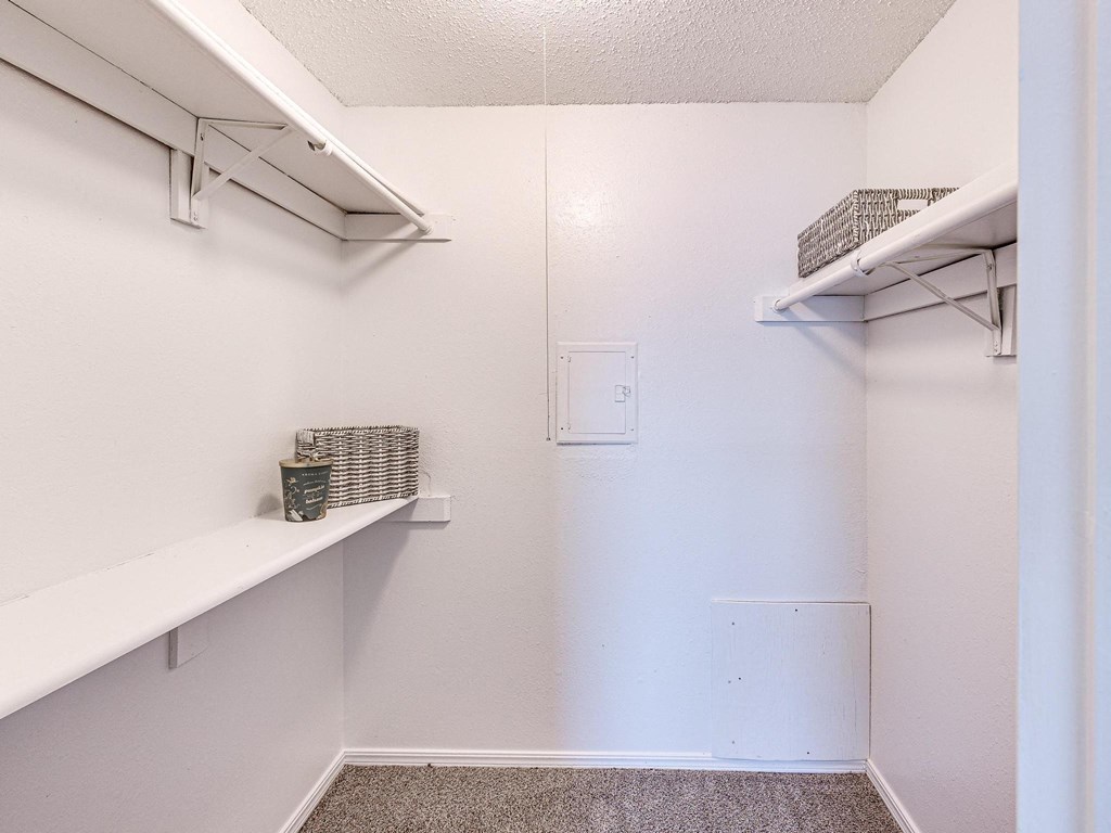 a walk in closet with shelves and two shelves on the wall