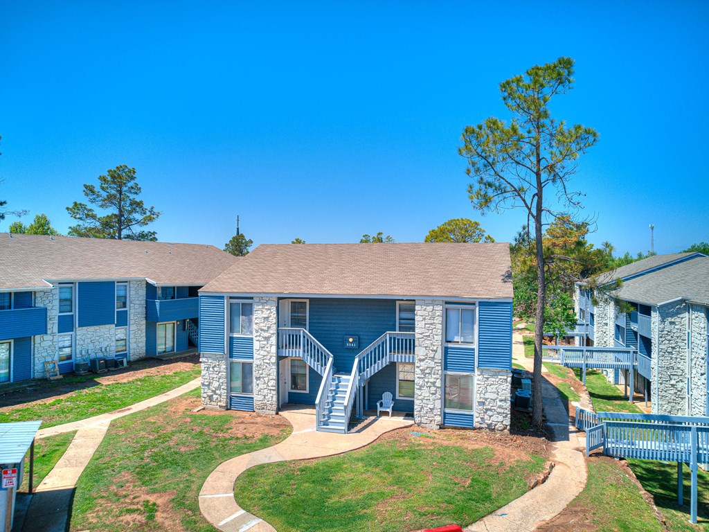 our apartments feature a spacious courtyard with trees and a blue building with stairs