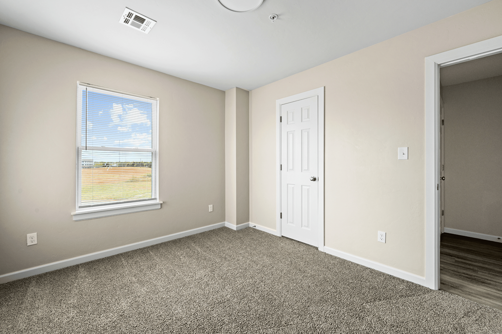 an empty bedroom with a door and a window an empty bedroom with a door and a window at Diamond Ridge Townhomes, Oklahoma City, OK