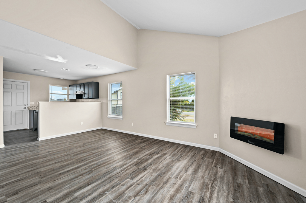 an empty living room with a fireplace and a kitchen at Diamond Ridge Townhomes, Oklahoma City