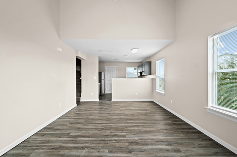 an empty living room and kitchen with wood flooring and a window