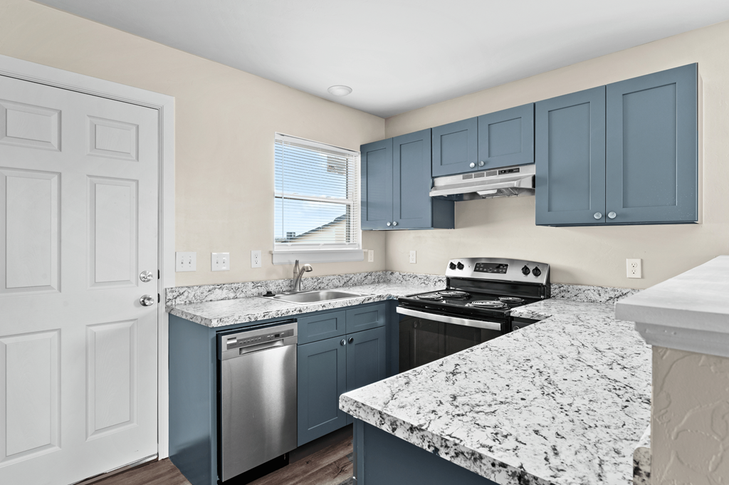 an updated kitchen with granite counter tops and blue cabinets at Diamond Ridge Townhomes, Oklahoma City, 73114
