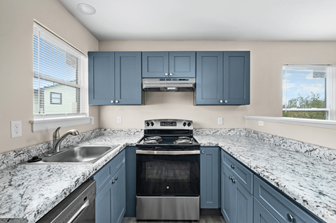 A kitchen with blue cabinets and granite countertops.