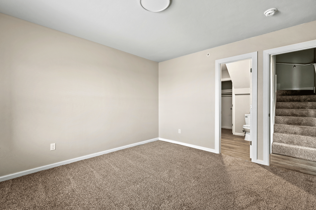 an empty living room with carpeting and a doorway to a bathroom at Diamond Ridge Townhomes, Oklahoma City, OK 73114