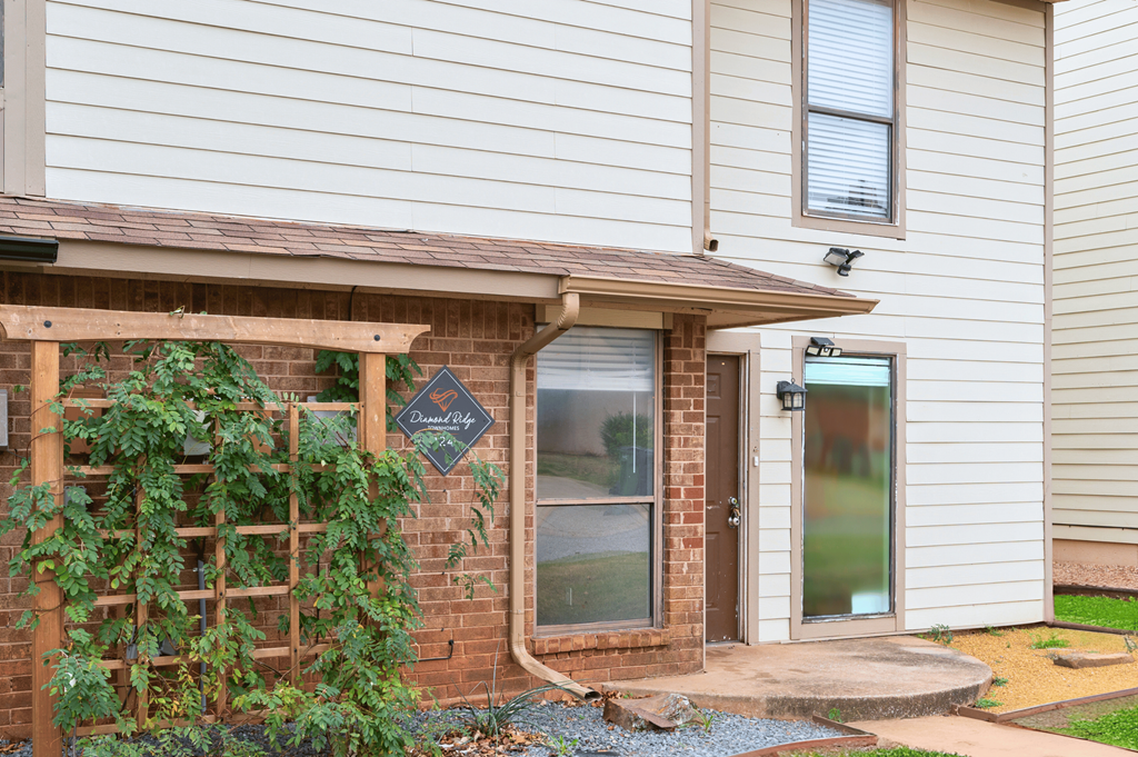 the front porch of a house with a brick wall and a door at Diamond Ridge Townhomes, Oklahoma City