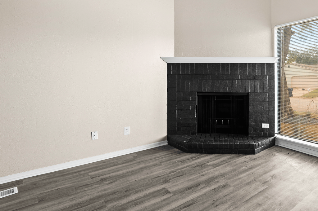 an empty living room with a fireplace and a window at Diamond Ridge Townhomes, Oklahoma City, OK 73114