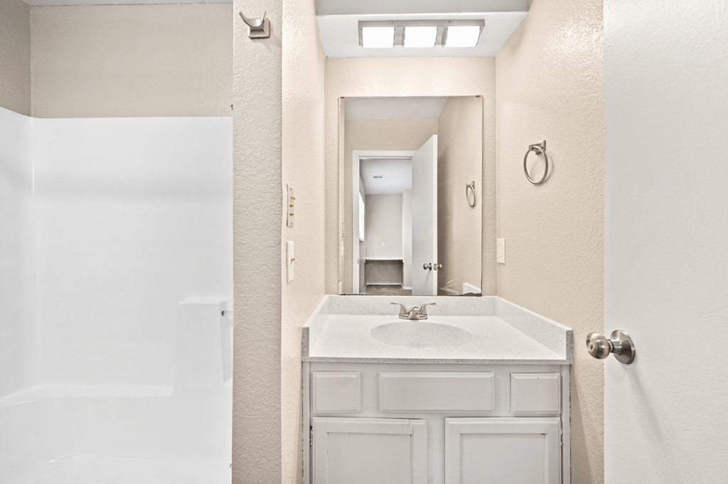 a bathroom with a sink and a mirror and a shower at Diamond Ridge Townhomes, Oklahoma City