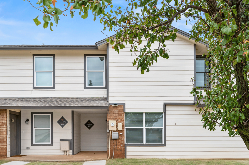 a white house with a tree in front of it at Diamond Ridge Townhomes, Oklahoma City, OK