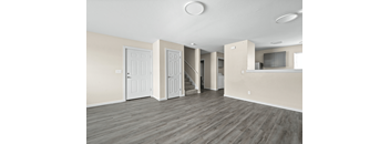 A spacious room with wooden floors and white walls.