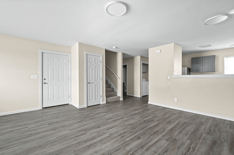 A spacious room with wooden floors and white walls.
