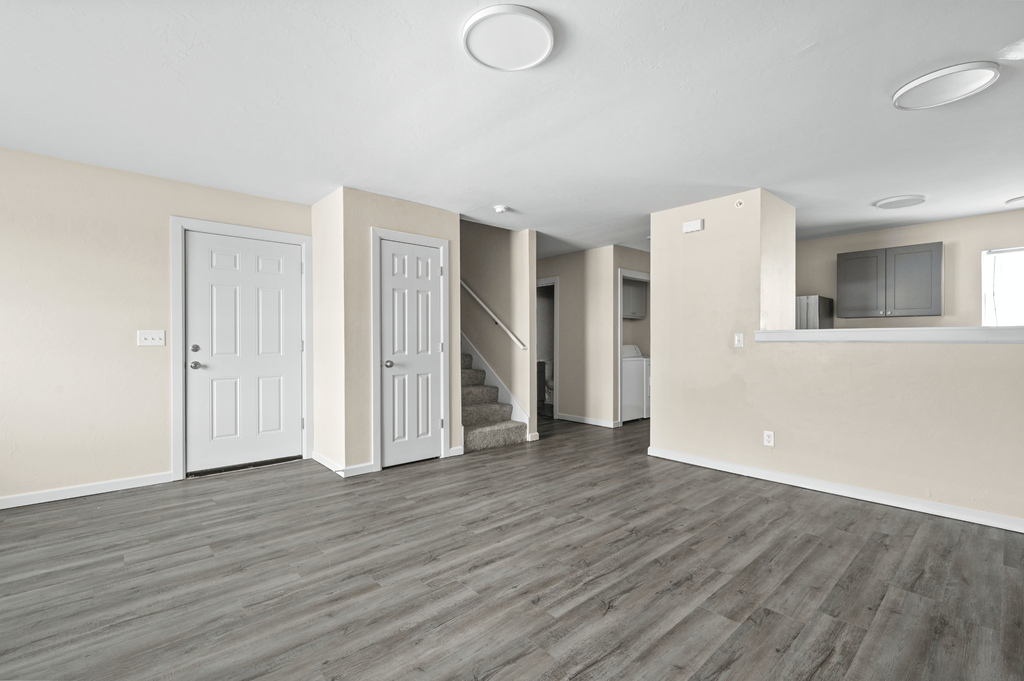 an empty living room with white walls and wood flooring at Diamond Ridge Townhomes, Oklahoma