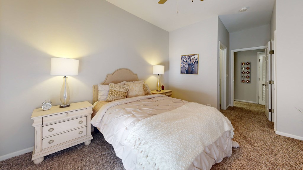 a bedroom with a bed and a dresser with two lamps at Dwell at Naperville, Naperville, 60563