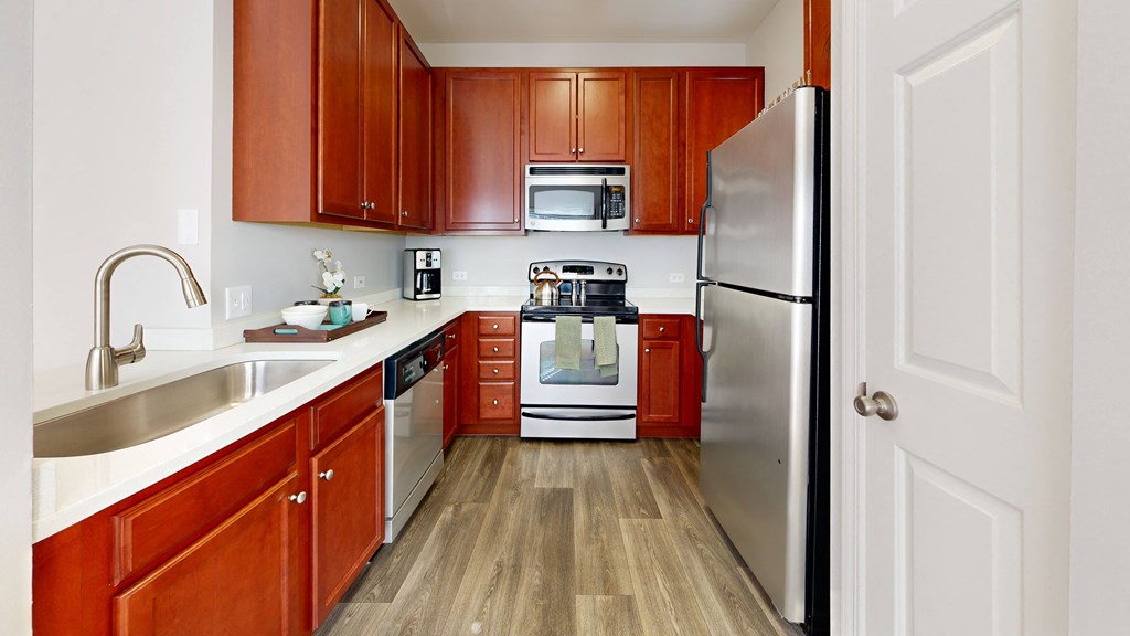 a kitchen with wooden cabinets and stainless steel appliances at Dwell at Naperville, Naperville, Illinois