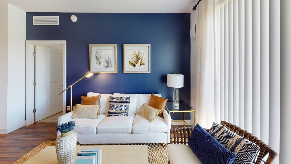 a living room with a blue accent wall and a white couch at The Lotus at Village Walk, Fort Myers, FL