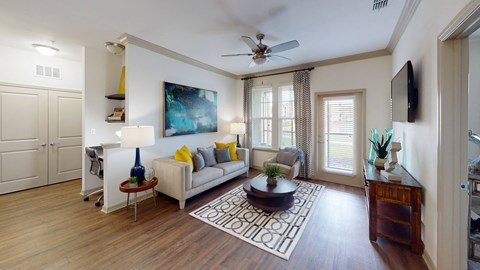 A living room with a white couch, a blue vase, and a painting on the wall.