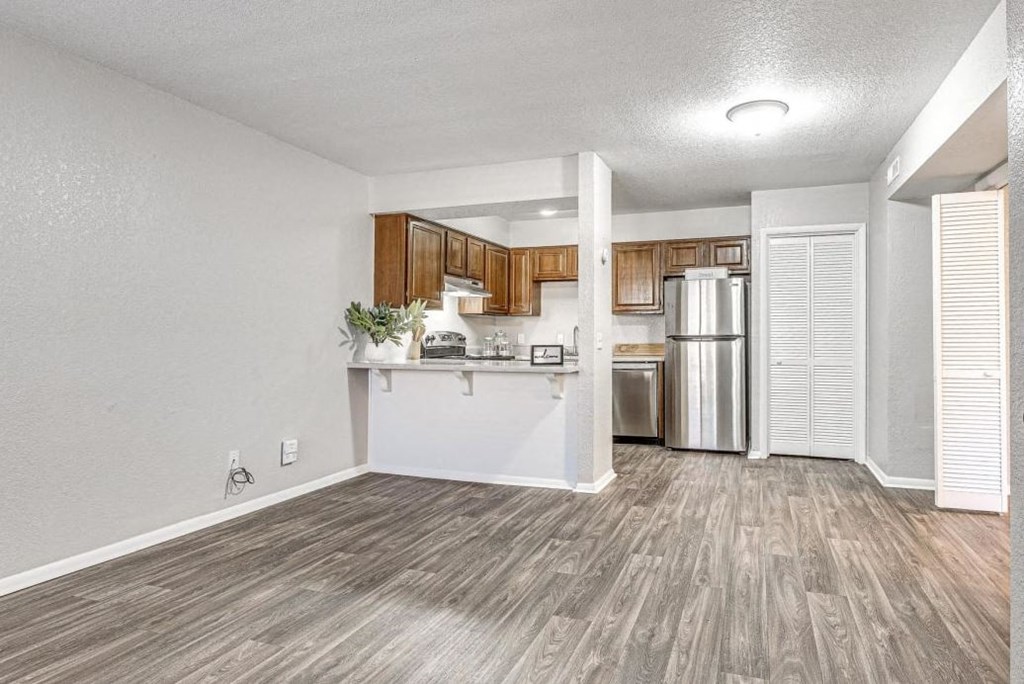 an empty living room and kitchen with a refrigerator