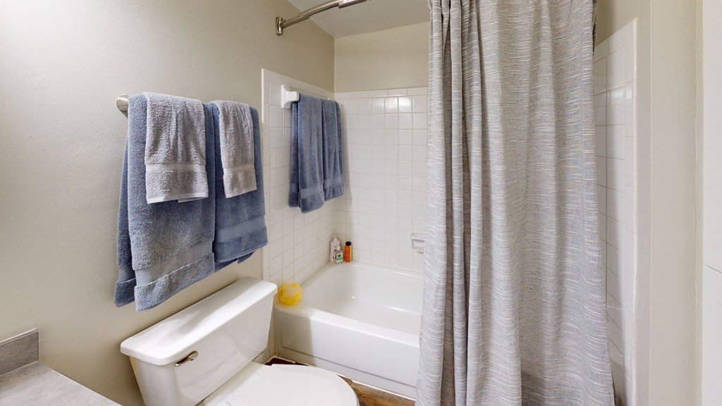 a bathroom with a white toilet next to a bathtub with a shower curtain at Laurel Oaks Apartments, Florida