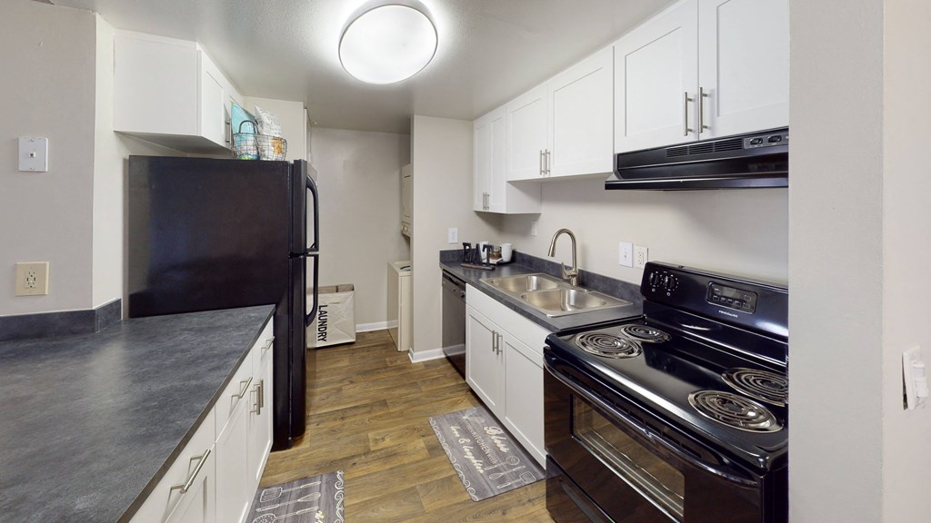 a kitchen with white cabinets and black appliances at Laurel Oaks Apartments, Tampa