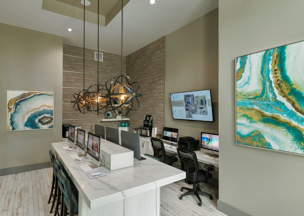 a reception area with computers and a large painting on the wall