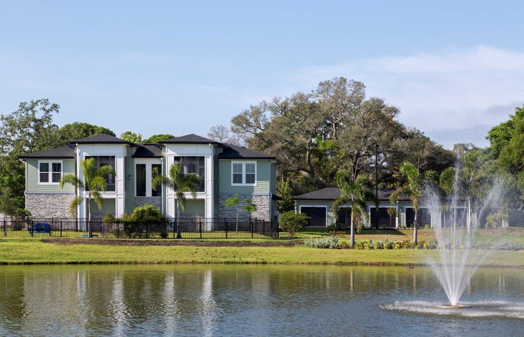 a fountain in the lake with houses in the background