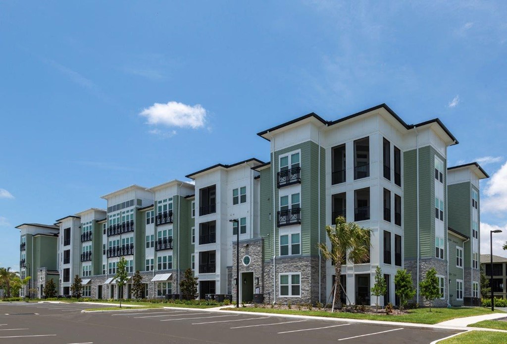 an exterior view of an apartment building with a parking lot