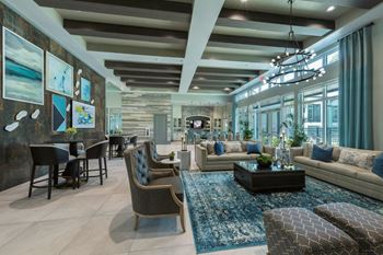 A modern living room with a variety of seating options and a large window at The Addison on Long Bayou Apartments, Seminole, FL
