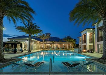 A large swimming pool surrounded by palm trees and lounge chairs at The Addison on Long Bayou Apartments, Seminole