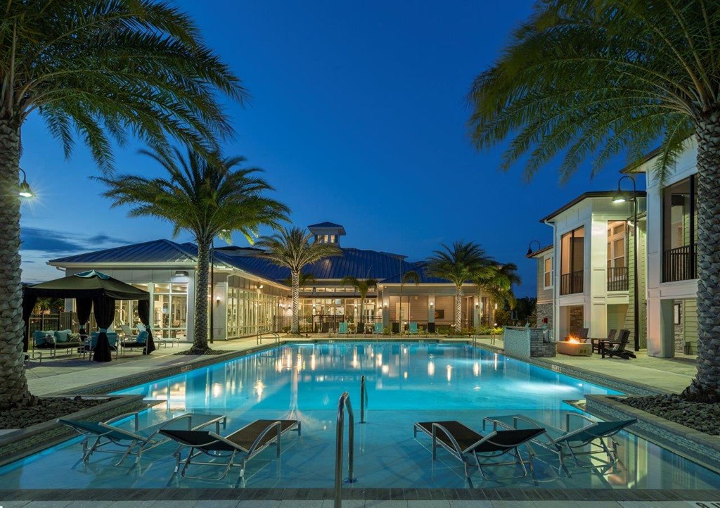 a large swimming pool in front of a hotel at night