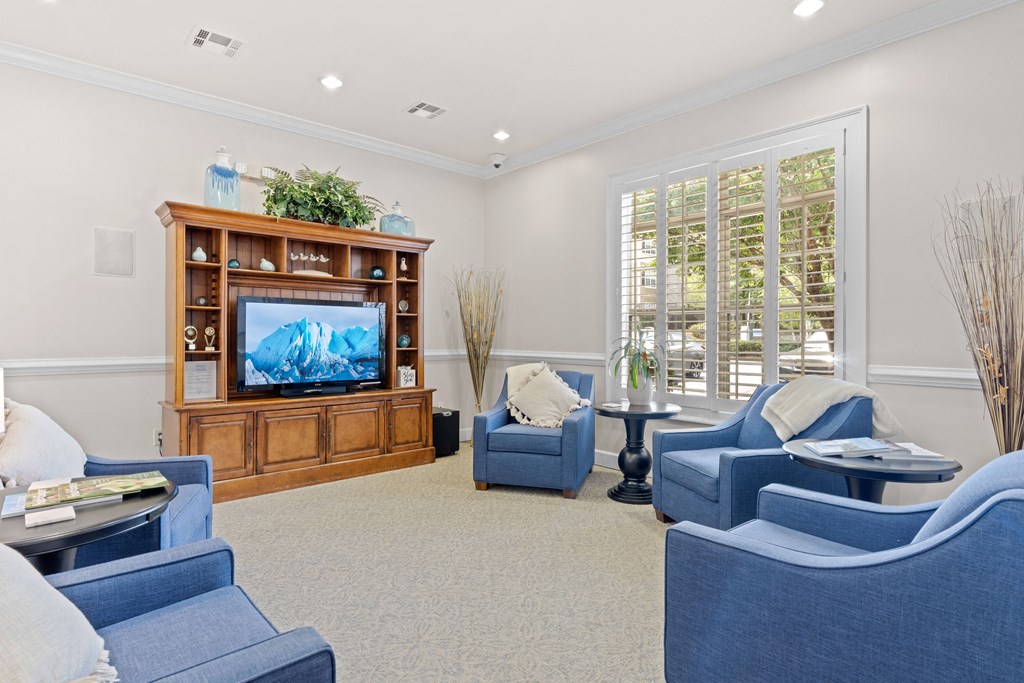 a living room with blue chairs and a television