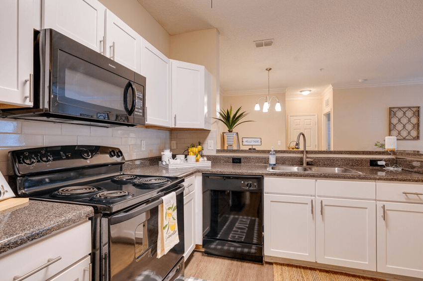 a kitchen with white cabinets and black appliances