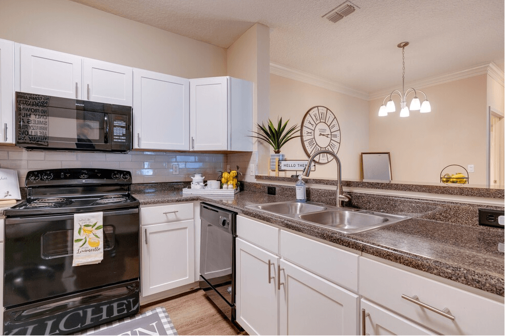 a kitchen with white cabinets and black appliances at Magnolia Village Apartments, Jacksonville
