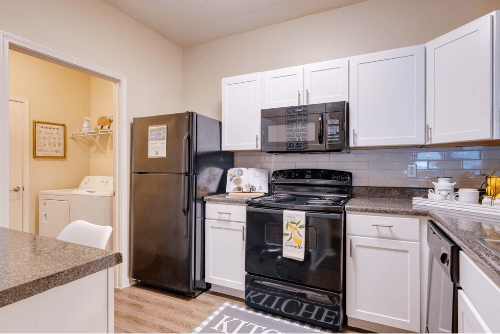 a kitchen with white cabinets and black appliances at Magnolia Village Apartments, Florida 32207