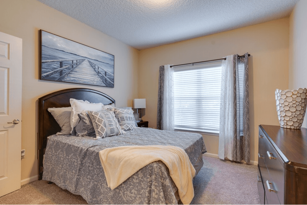 a bedroom with a bed and a dresser at Magnolia Village Apartments, Florida