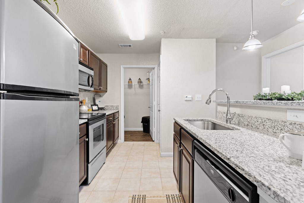 a kitchen with white granite countertops and stainless steel appliances