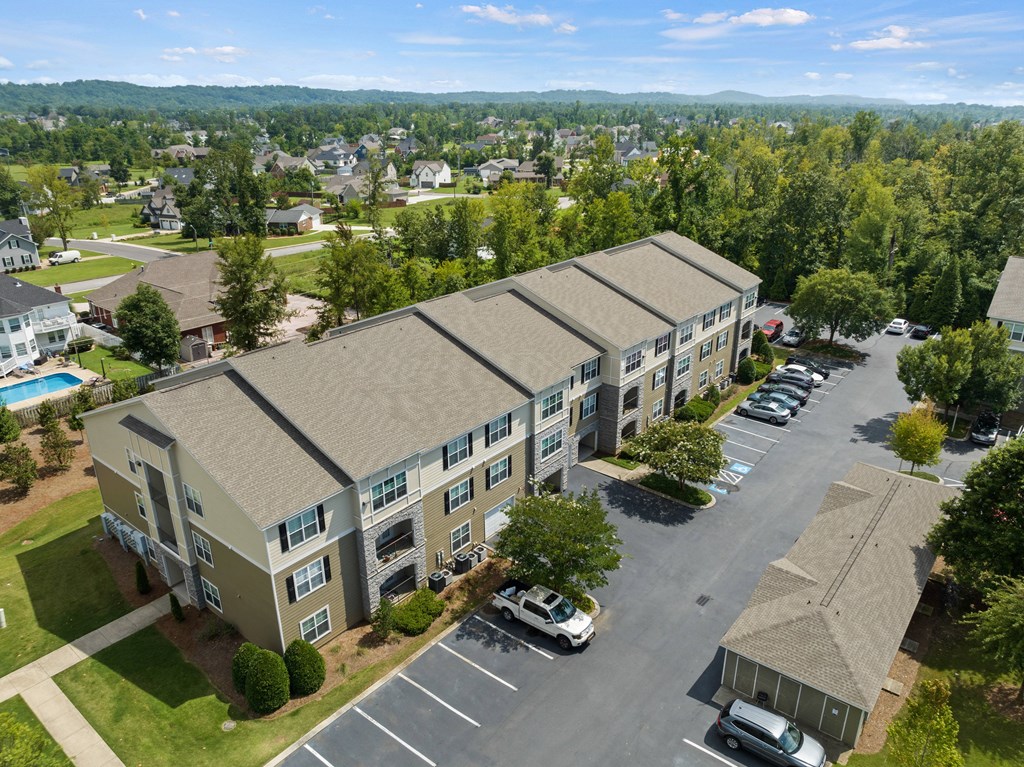 an aerial view of an apartment complex with a swimming pool and parking lot