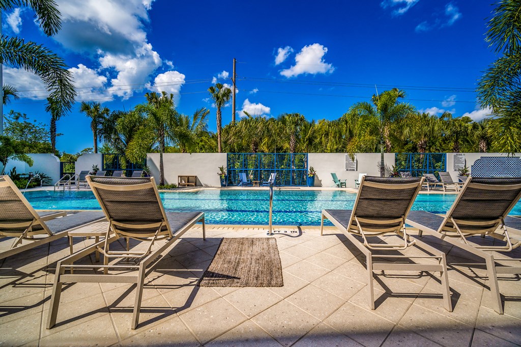 a swimming pool with chairs and a blue sky at Magnolia Square, Naples, 34109