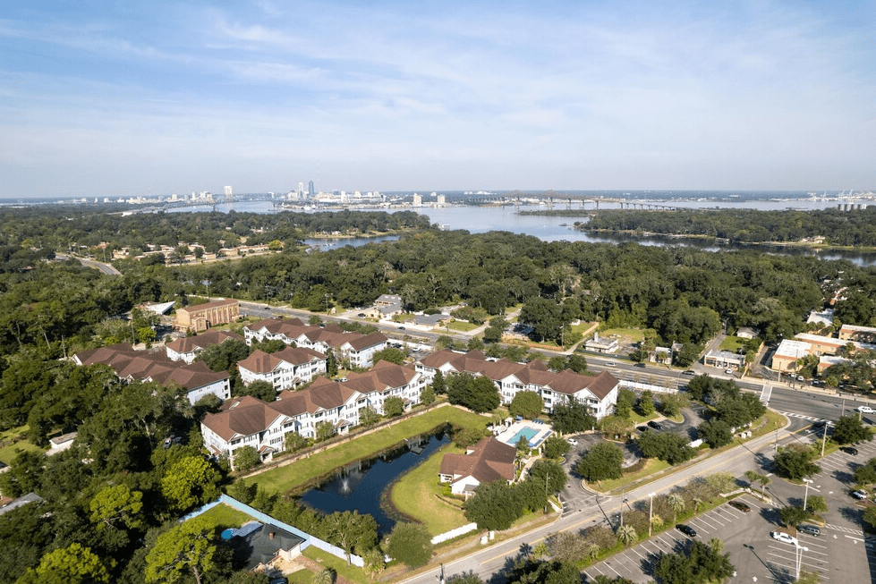 an aerial view of a neighborhood with a lake and a city in the background at Magnolia Village Apartments, Jacksonville, 32207