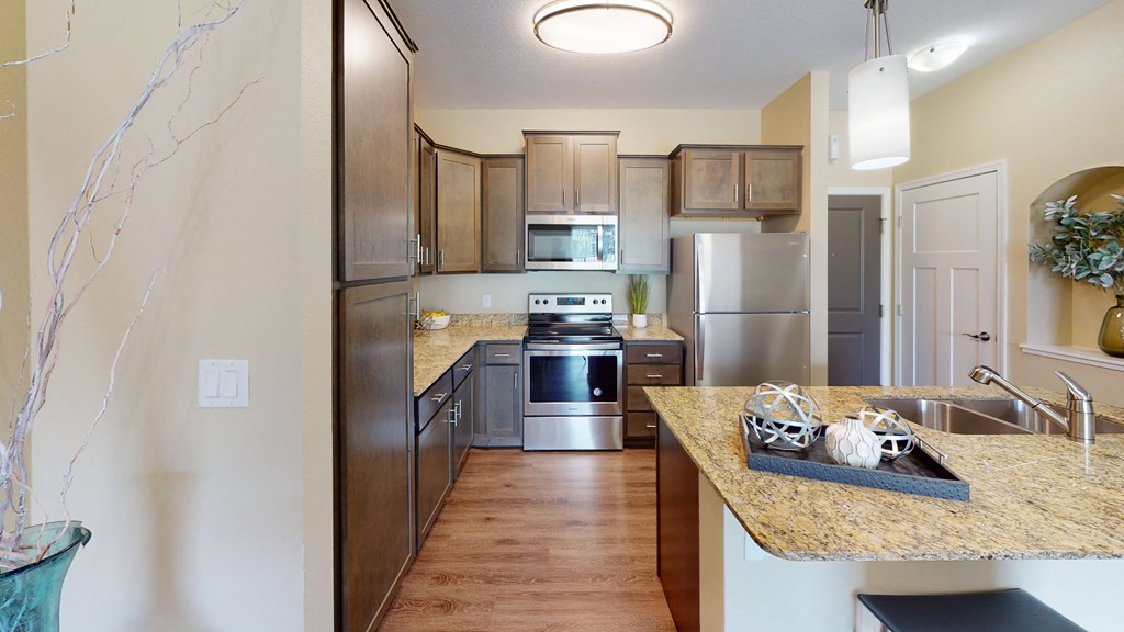 a kitchen with wooden cabinets and stainless steel appliances at Skye at Arbor Lakes, Maple Grove, Minnesota