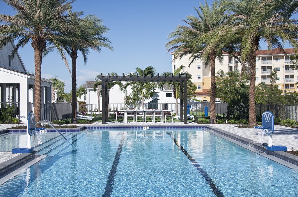 a large swimming pool with a pergola and palm trees in the background at Odyssey, Fort Myers, Florida