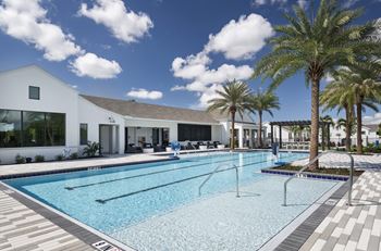 a swimming pool with palm trees in front of a house at Odyssey, Florida