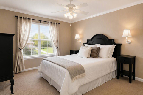 A bedroom with a large bed and a window with curtains.
