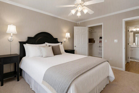 A bedroom with a large bed and a ceiling fan.