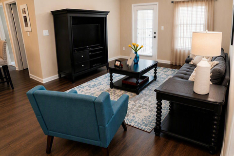 A living room with a blue chair and a black cabinet.