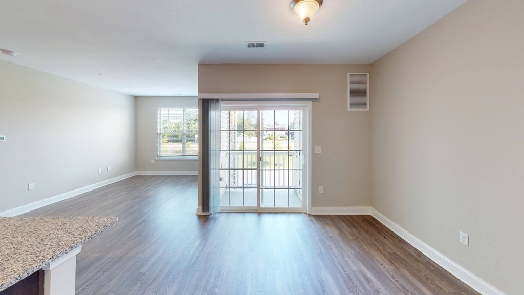 a bedroom with hardwood flooring and a door leading to a balcony at The Landing Apartments, Hazlet, New Jersey