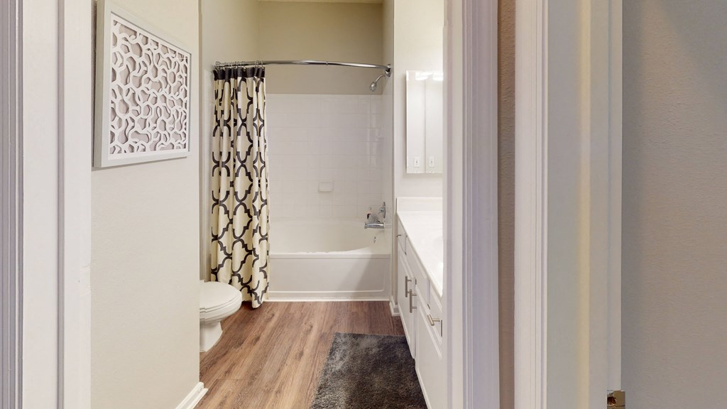 a bathroom with a white bathtub and a white toilet with a black and white shower curtain  at The Preserve at Tampa Palms, Tampa, 33647
