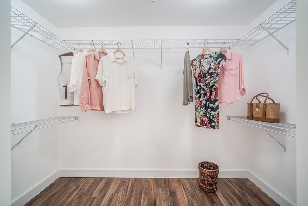 a walk in closet with a rack of clothes and a basket on the floor at The Lotus at Village Walk, Fort Myers, 33966