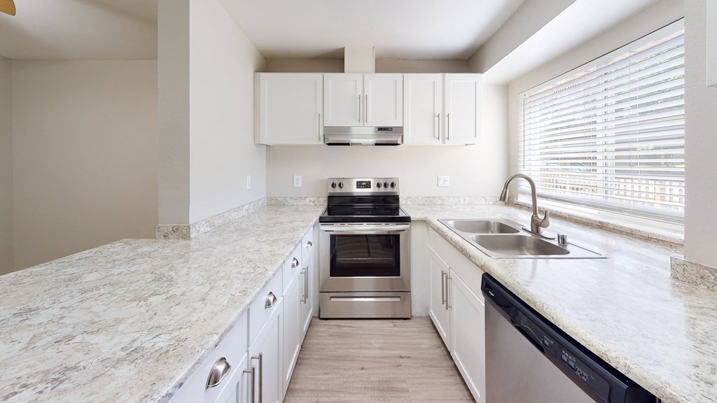 a kitchen with white cabinets and a large window