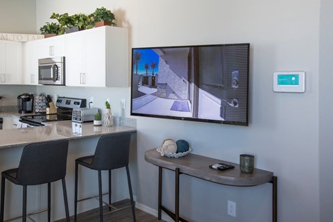 A modern kitchen with a bar area and a television displaying a street view.